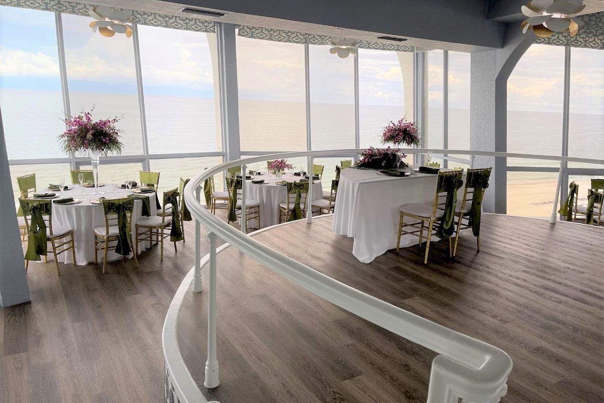 Elegant seaside dining space with tables set for a meal and ocean view.