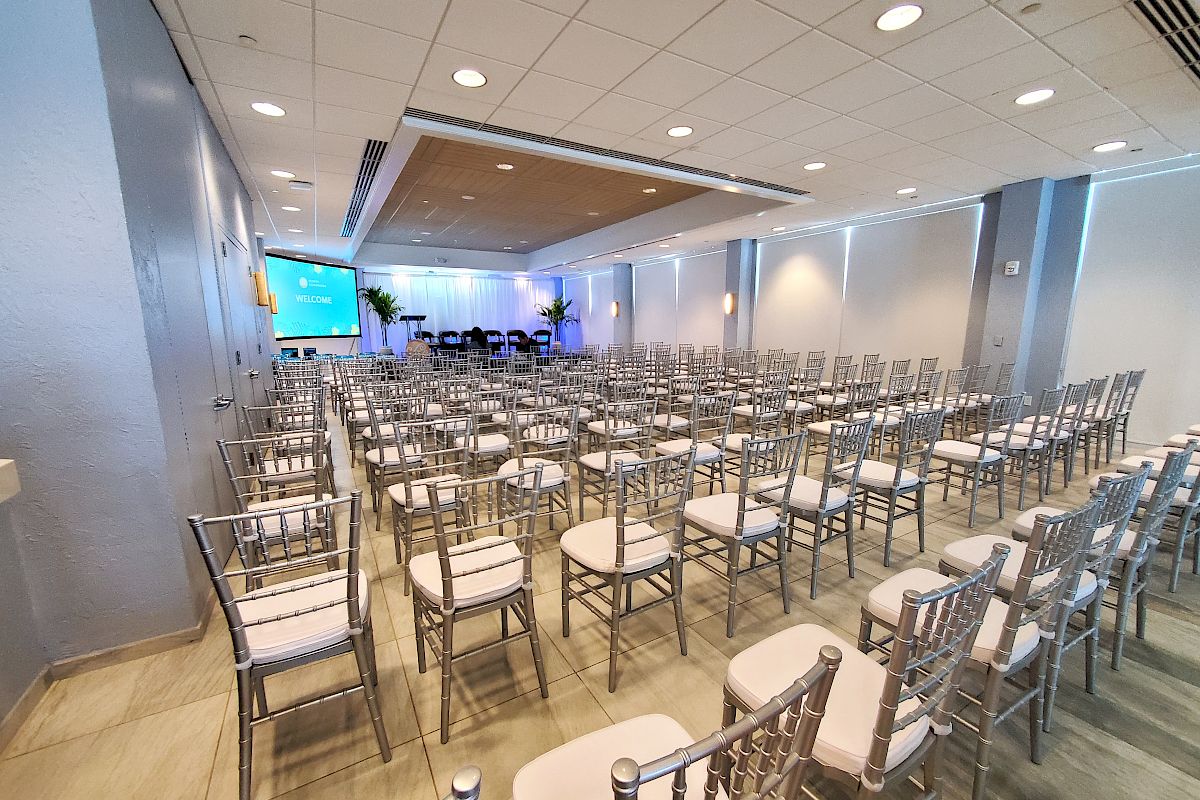 An empty conference room with rows of chairs and a presentation screen at the front.