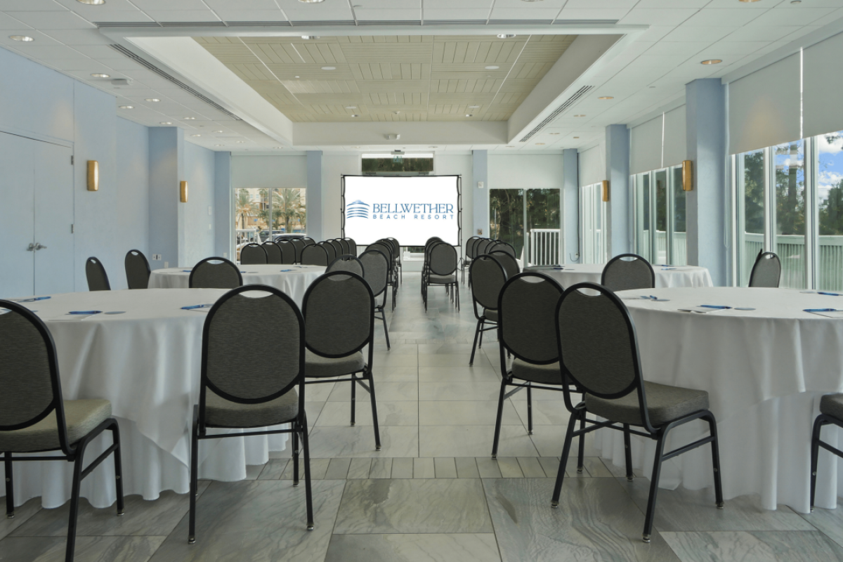 Empty conference room with tables, chairs, and a presentation screen.
