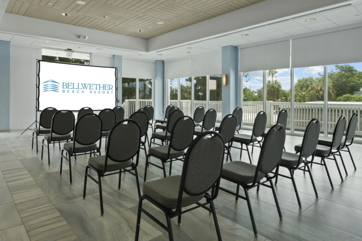 An empty meeting room with chairs facing a screen displaying a logo.