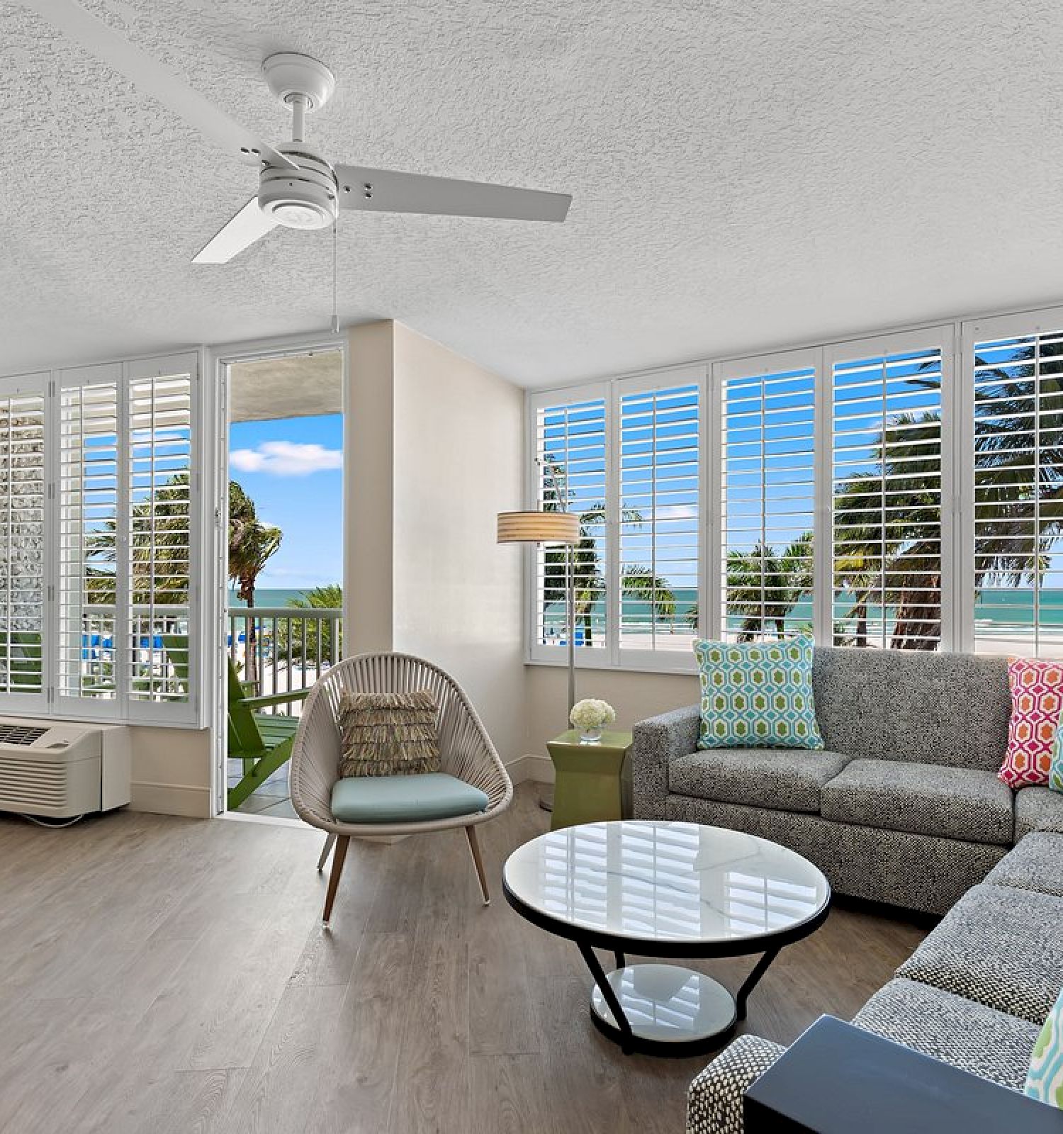 Bright living room with a sofa, chair, and beach view from the window.