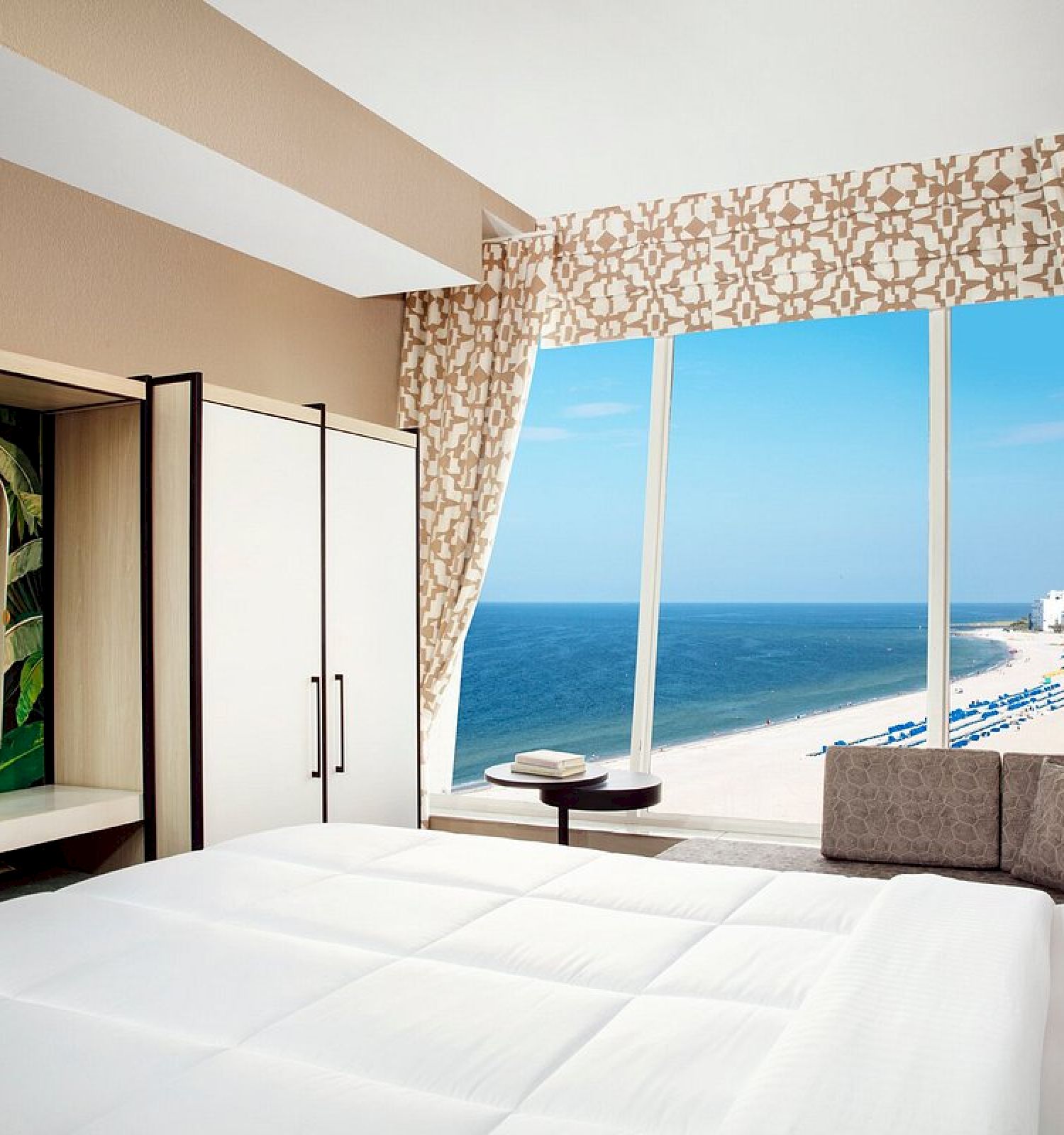 A modern bedroom with a large bed, ocean view, and elegant decor.