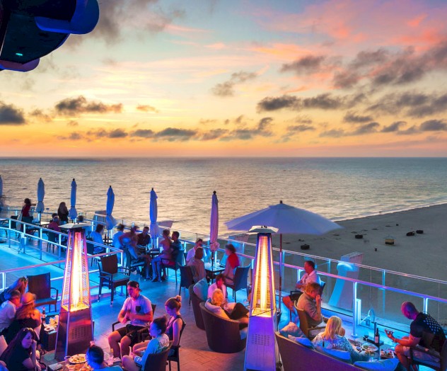 Beachside rooftop bar with people enjoying evening views.
