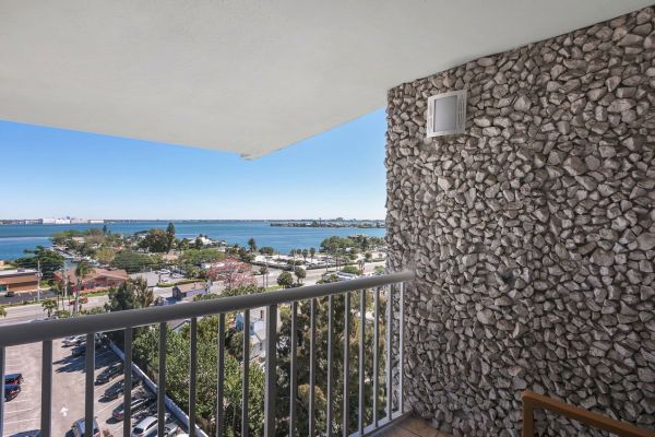 Balcony with stone wall overlooking a coastal view with blue skies.