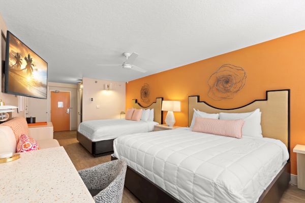A bright hotel room with two beds, artwork on walls, and modern decor.