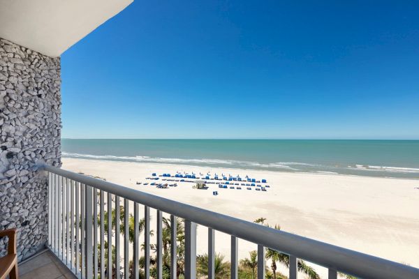 Balcony view of a beach with umbrellas, calm sea, and clear sky.