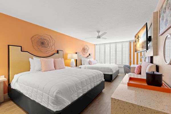 Bright hotel room with two beds, artwork, and modern decor.