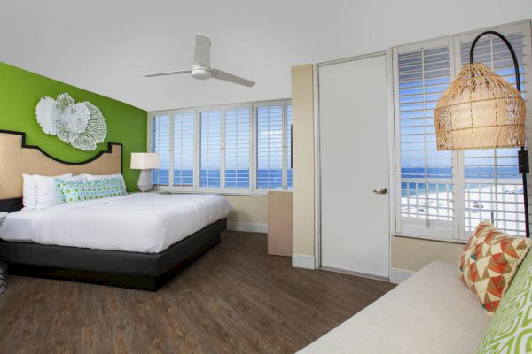 A bright beachfront room with a bed, sea view, artwork, and bold decor.