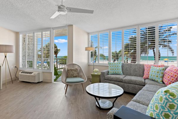 Beachfront living room with modern furniture and ocean view through large windows.