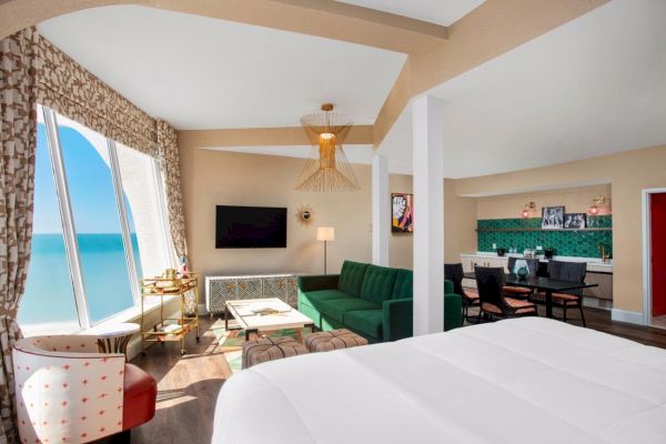 Bright hotel room with bed, green sofa, and seaside view.