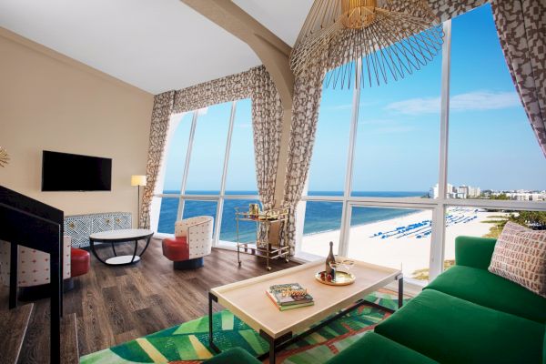 Bright beachfront room with large windows, chic decor, and a stunning ocean view.