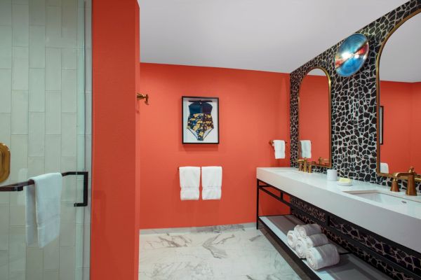 A vibrant bathroom with orange walls, a large mirror, and modern decor.