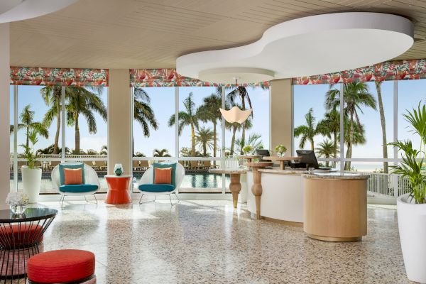 Luxurious tropical resort lobby with stylish furniture, overlooking palm trees and pool.