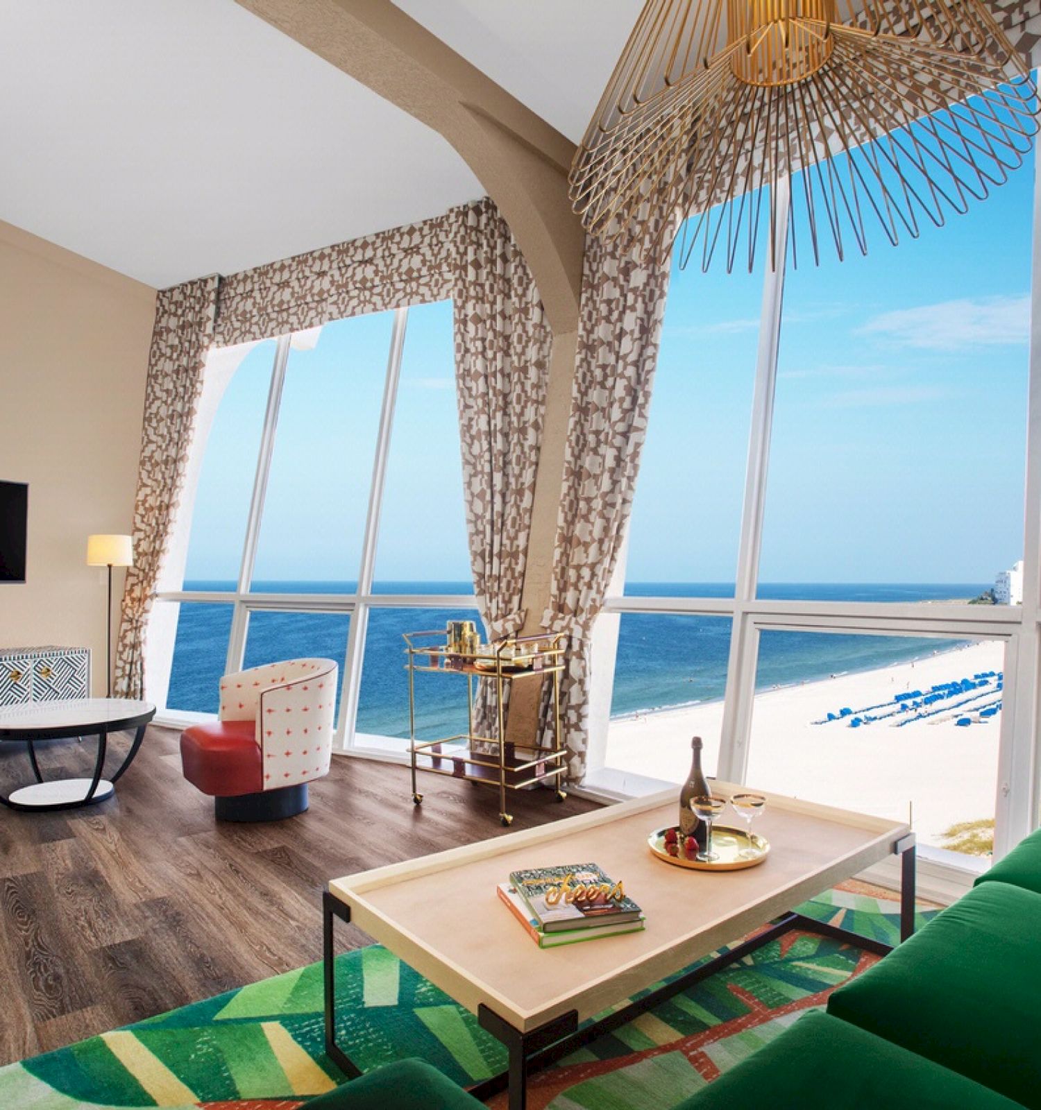 A beachfront room with a sofa, table, TV, large windows, and a seaside view.