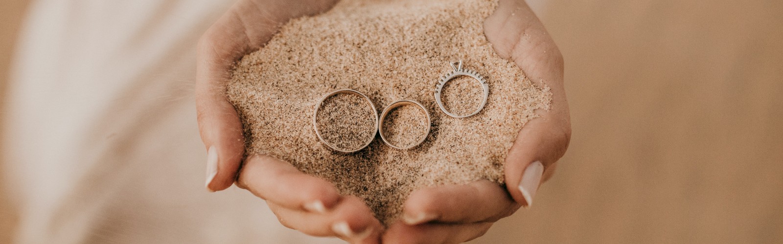 Hands holding sand with three rings.