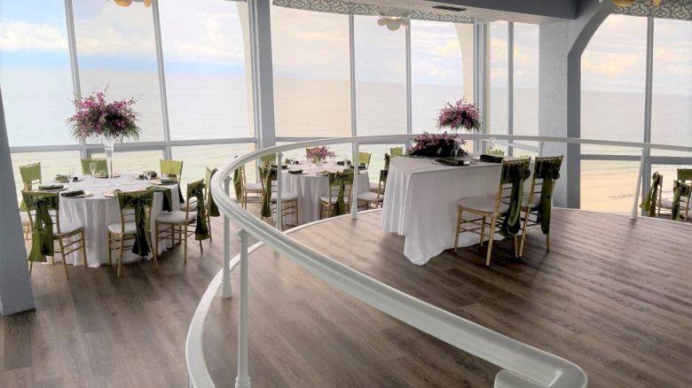 Elegant seaside dining space with tables set for a meal and ocean view.