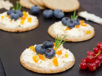 Crackers with cheese, blueberries, apricot, and herbs.