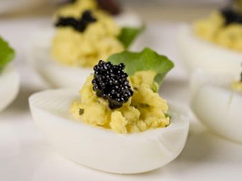 Deviled eggs topped with caviar and garnished with greens.