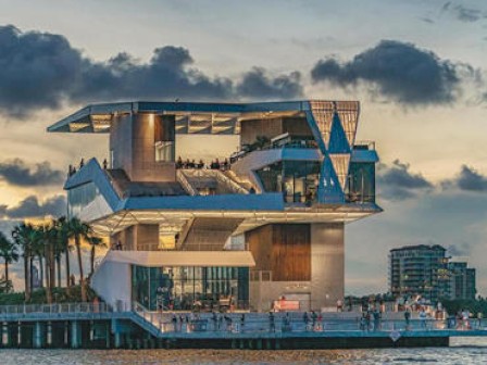 A modern building by the water during sunset.