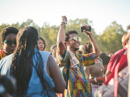 People enjoying an outdoor event with one person raising their arm and holding a camera.