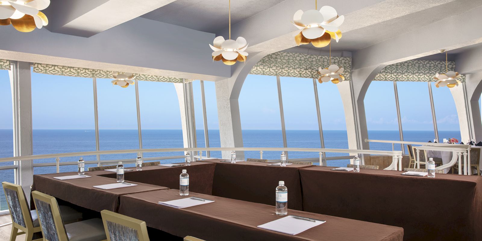 Elegant dining area by the sea with stylish lighting and modern decor.