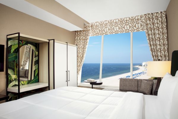 A hotel room with a bed, ocean view, and modern decor.