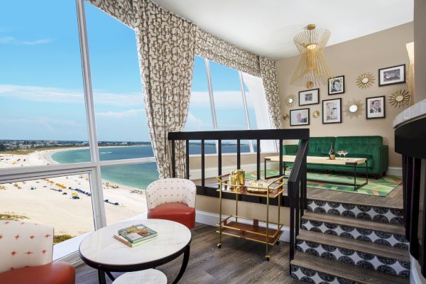 A stylish room with a sea view, eclectic furnishings, and framed pictures on the wall.