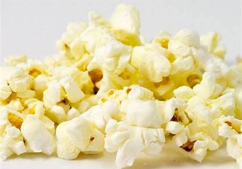 This image shows a close-up of a pile of freshly popped popcorn on a light background, ready for snacking.