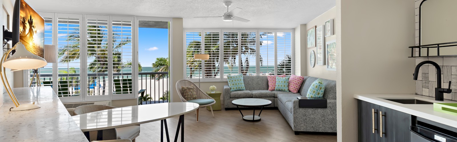 Bright, modern apartment interior with an open-plan kitchen and living space, leading to a balcony with a view.