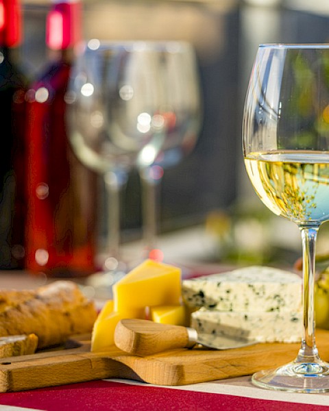 Glass of white wine with a selection of cheese and fruit.