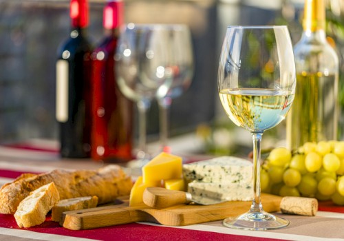 Glass of white wine with a selection of cheese and fruit.