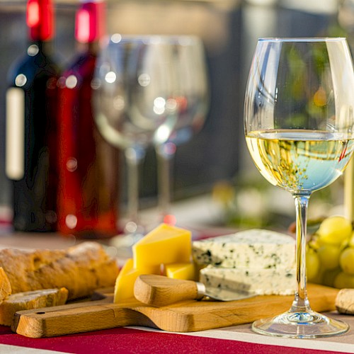 Glass of white wine with a selection of cheese and fruit.