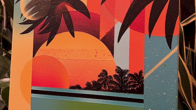 The image shows a colorful, abstract painting of a tropical sunset with palm trees and geometric shapes, set against a backdrop of plants.