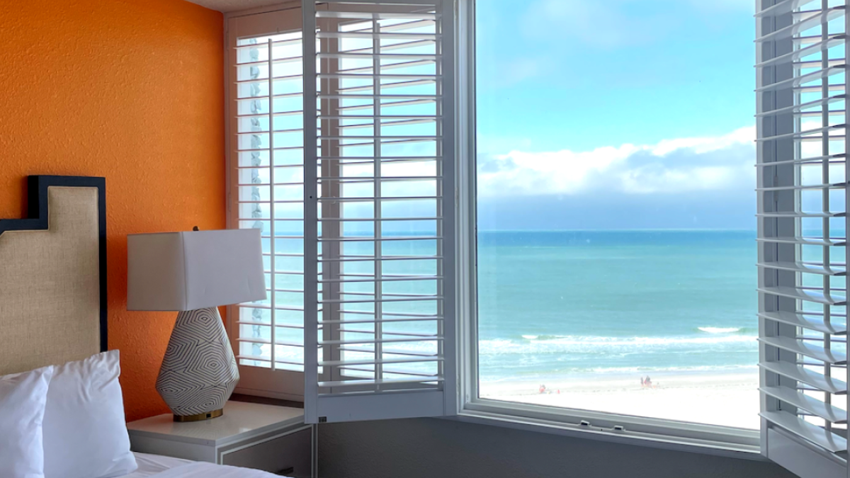 This image shows a beautiful hotel room with an ocean view with a blue sky.