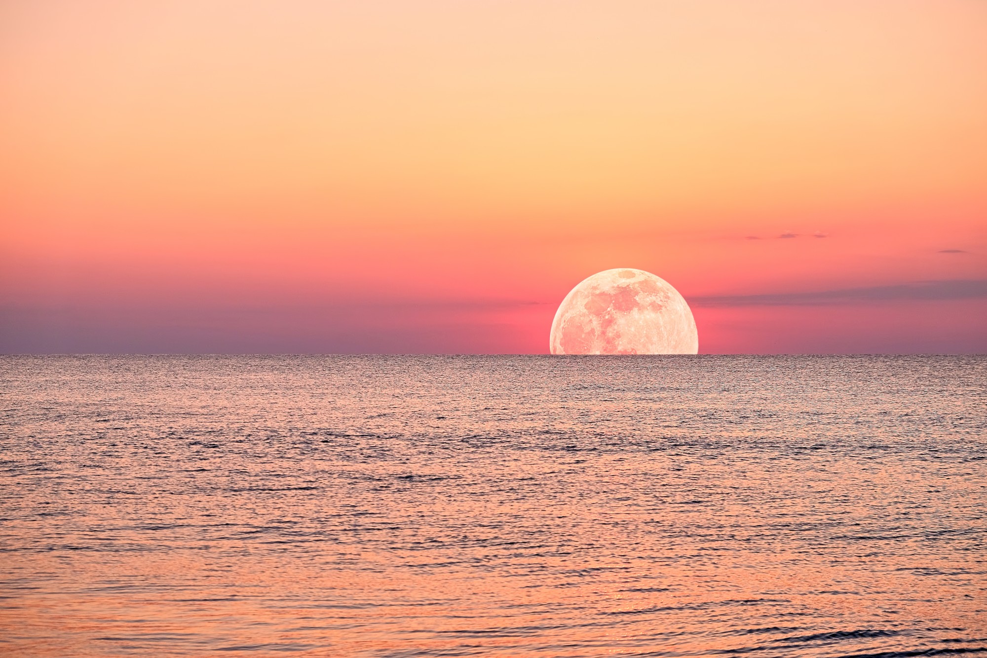 A full moon rises out above the Gulf of Mexico